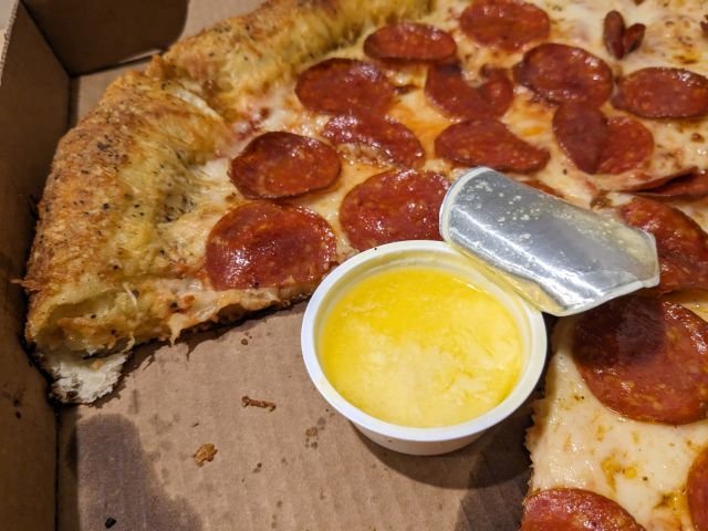 Papa Johns Garlic Epic Stuffed Crust Pizza with cups of buttery garlic sauce.