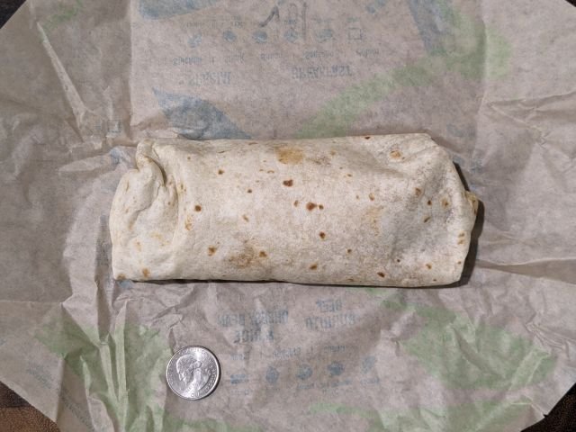 Taco Bell Double Beef Volcano Burrito with quarter for size comparison.