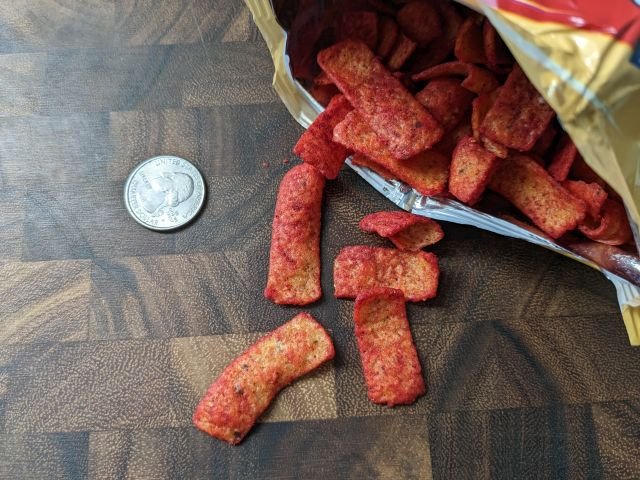 Flamin' Hot Bar-B-Q Fritos corn chips with quarter for size comparison.