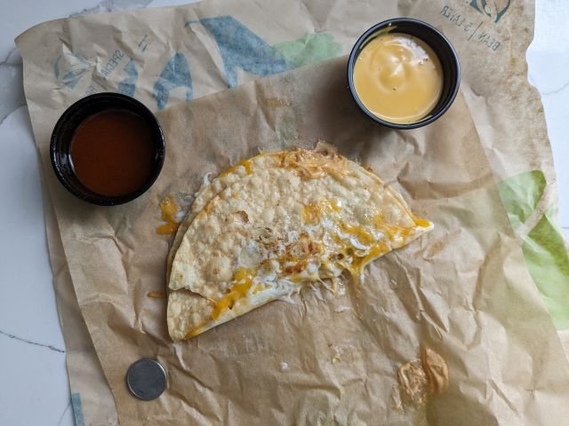 Taco Bell Grilled Cheese Dipping Taco with two dips and quarter for size comparison.