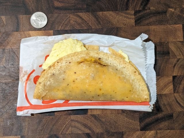 Jack in the Box Breakfast Taco top-down view with quarter for size comparison.